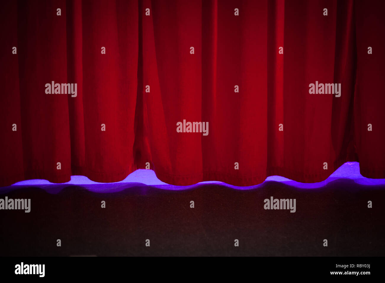 Rote Vorhang Kulisse auf der Bühne mit dezenter Beleuchtung. Stockfoto