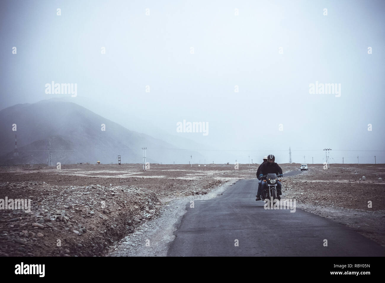 Zwei asiatische Männer reiten Motorrad- und Allradantrieb Auto fahren, folgen Sie ihnen auf der Landstraße nach Leh Stadt mit Himalaya Mountain Hintergrund bei Lada Stockfoto