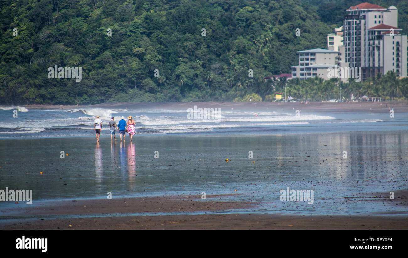 Ein Foto von vier Menschen zu Fuß auf die schönen und weitläufigen Sandstrand von Jaco, Costa Rica. Menschen werden unkenntlich. Stockfoto