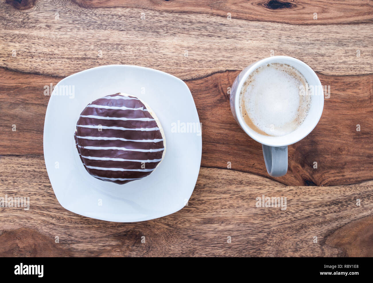 Schokolade überzogen jelly Donut und Tasse Kaffee auf hölzernen Tisch Stockfoto