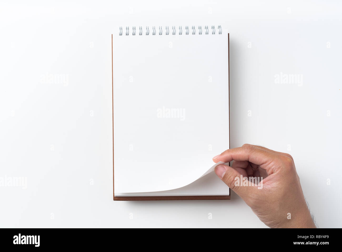 Designkonzept - Perspektivische Ansicht braun hardcover Spirale notebook, Hand des Menschen flip curl Seite auf Hintergrund für Mockup isoliert Stockfoto