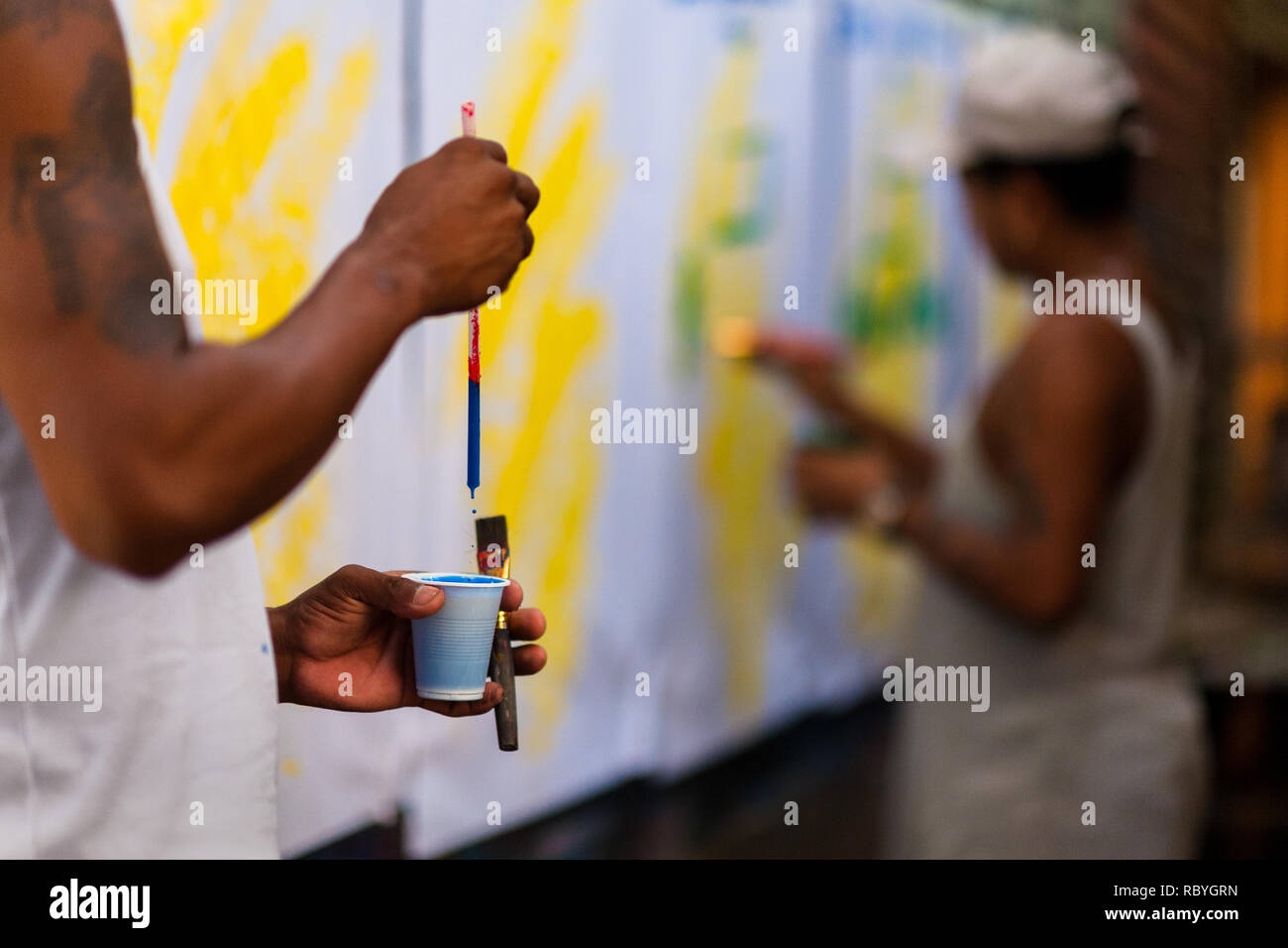 Eine kolumbianische Schildermaler bereitet seine Bürste, bevor Sie mit dem Schreiben von Buchstaben, die auf Musik Party Poster im Zeichen der Malerei Workshop in Cartagena, Kolumbien. Stockfoto