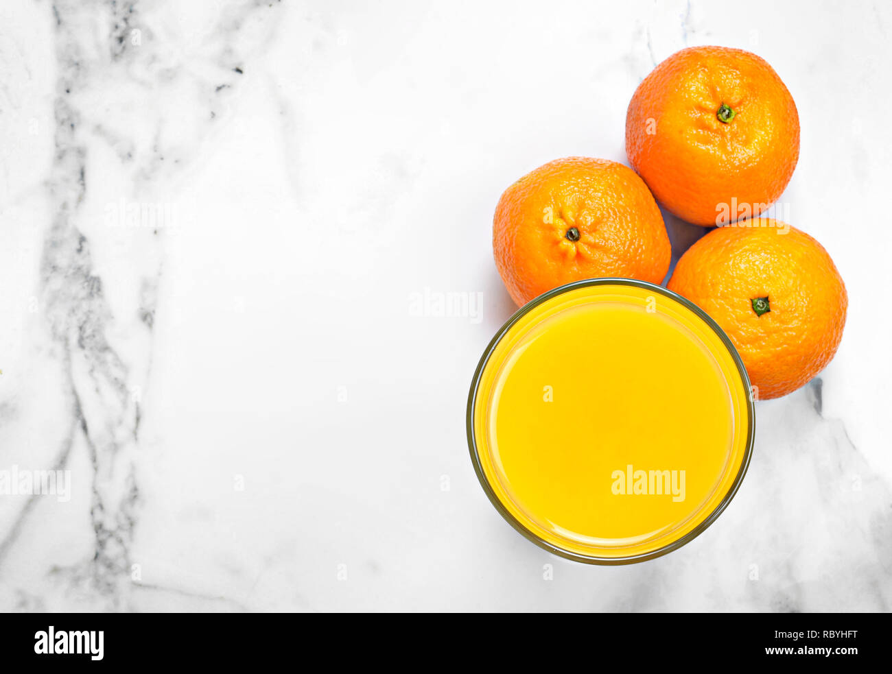 Frisch gepresster Orangensaft in einem Glas, Ansicht von oben. Gesunde Fruchtsäfte auf weißem Marmor oder Stein. Stockfoto