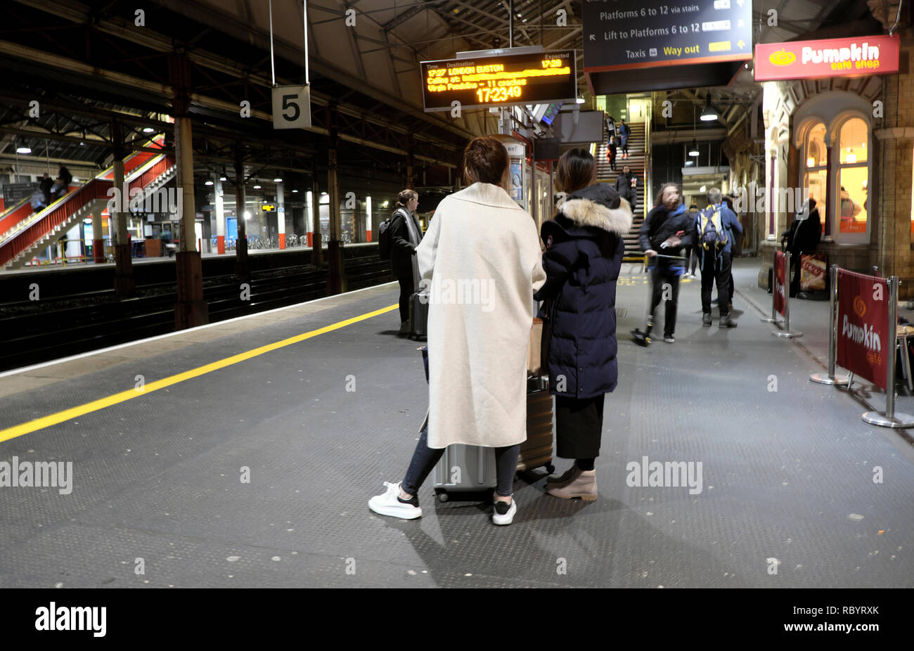 Ansicht der Rückseite des reisenden Frau tragen weiße Schicht auf der Plattform in Crewe Bahnhof warten auf eine Jungfrau Zug nach London UK KATHY DEWITT Stockfoto