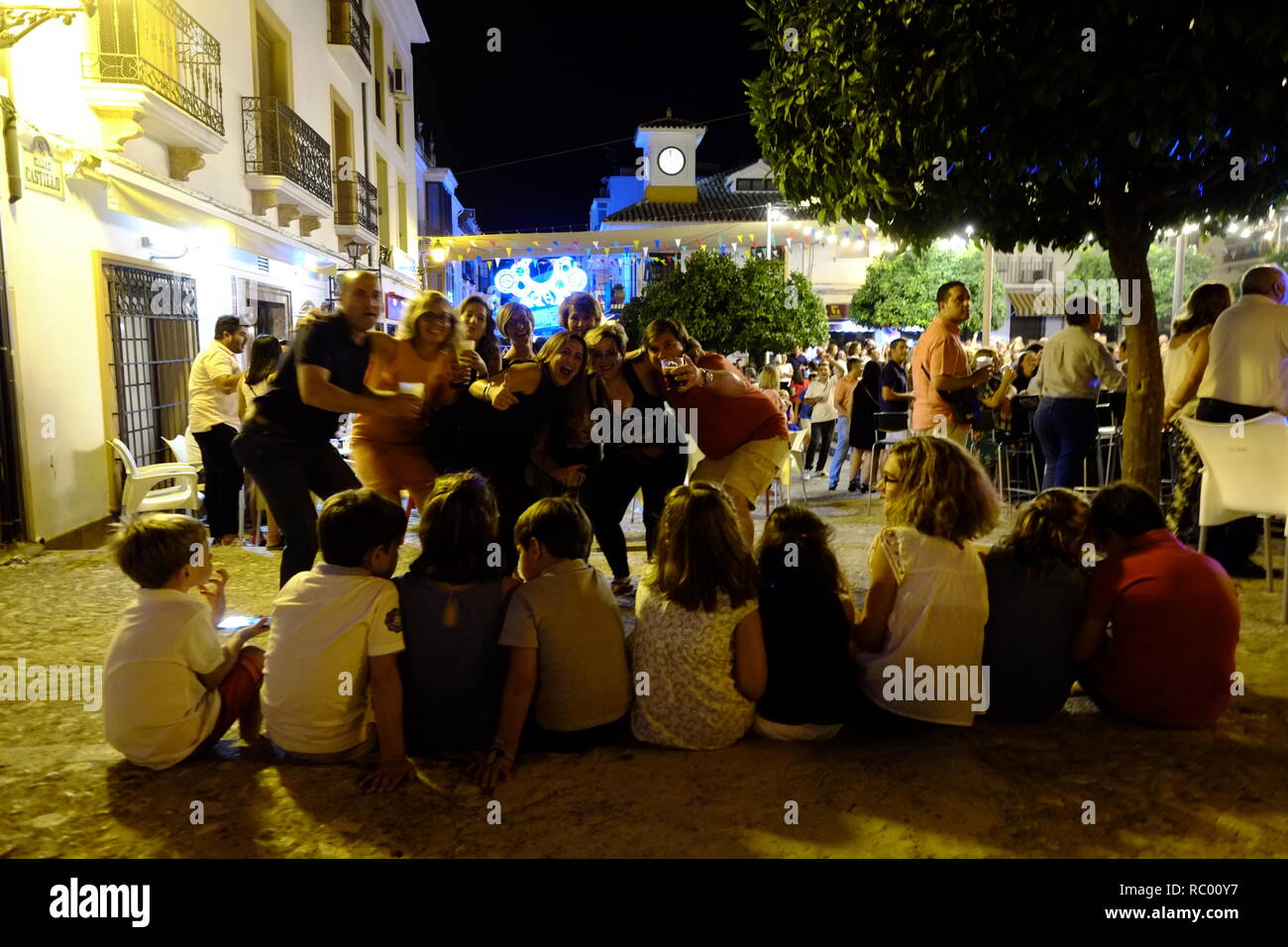 Ein Abend während der Sommerfesta und der Erwachsenen feiern, während die kleinen Kinder auf ihr Handy schauen. Carcabuey, Andalucia, Spanien. Stockfoto