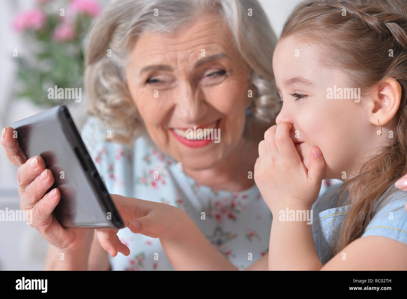 Süße kleine Mädchen mit ihrer Großmutter an Tablet suchen Stockfoto