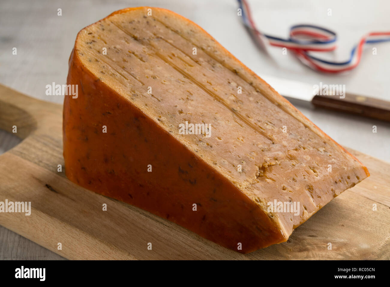 Stück des drei Jahre alten holländischen Kreuzkümmel käse auf einem hölzernen Schneidebrett Stockfoto