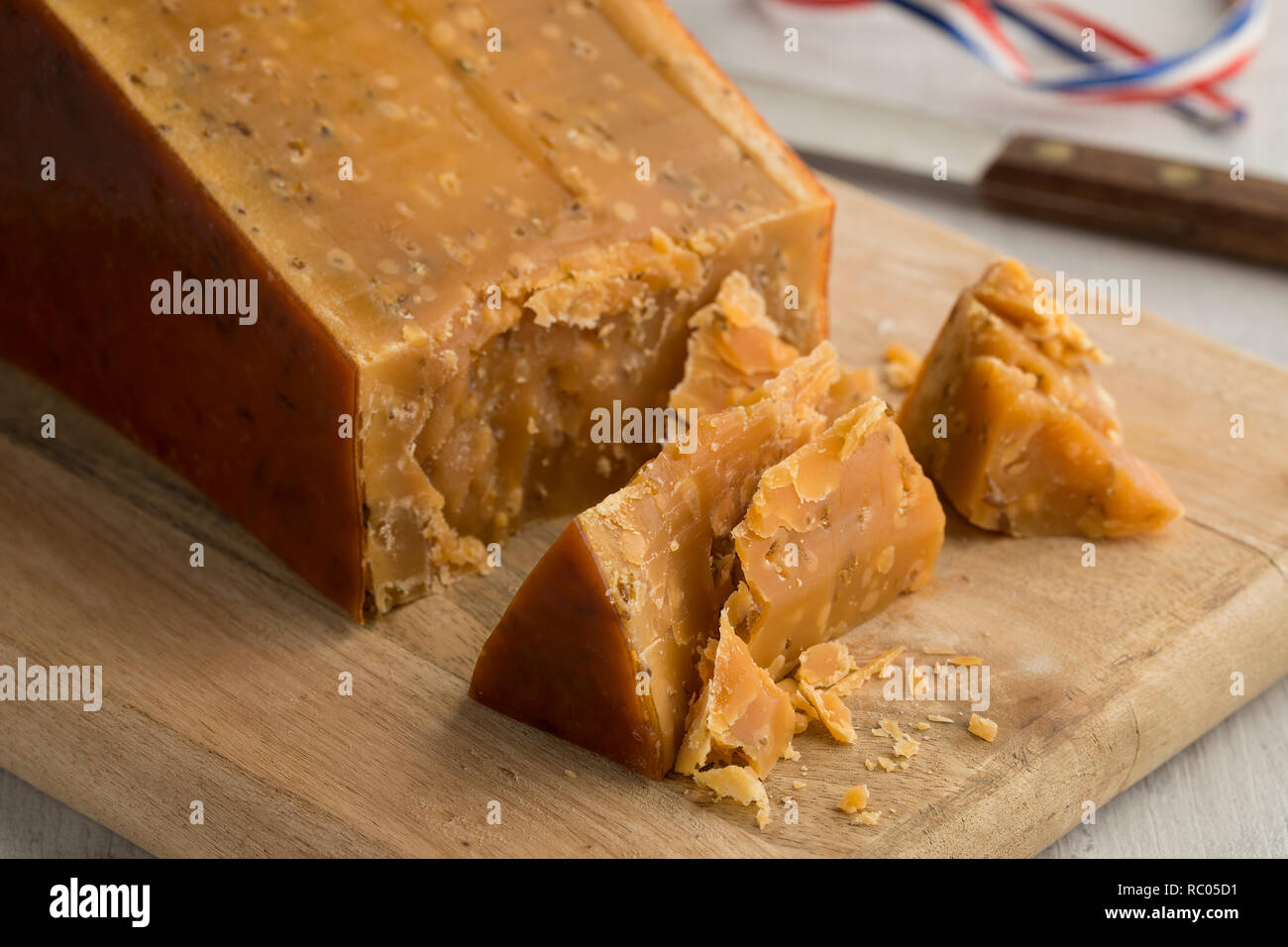 Stück des drei Jahre alten holländischen Kreuzkümmel käse mit bröckelt auf einer hölzernen Schneidebrett Stockfoto