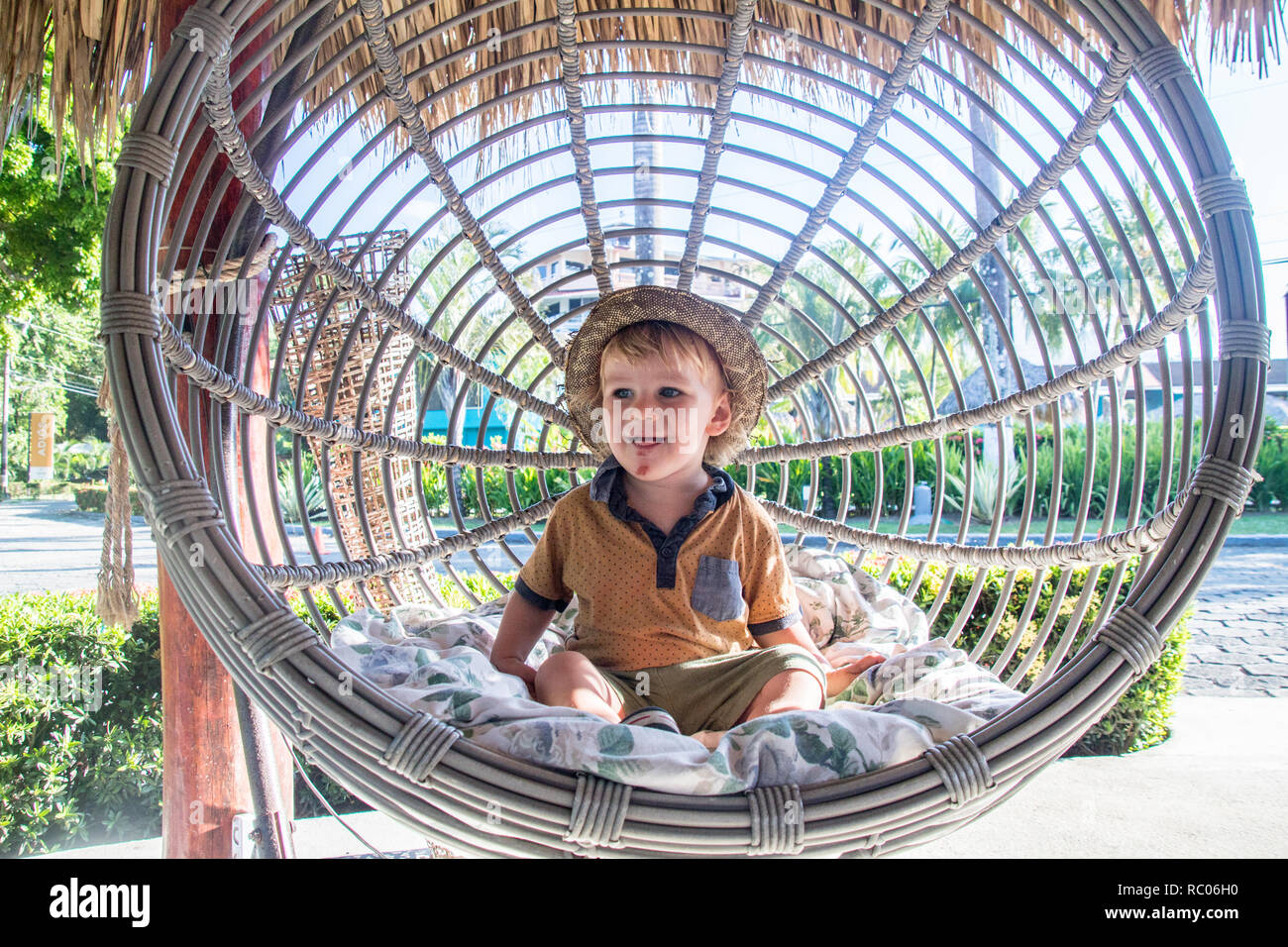 Ein Portrait eines Jungen mit einem Hut glücklich in einem schönen Garten Schaukel Stuhl Stockfoto