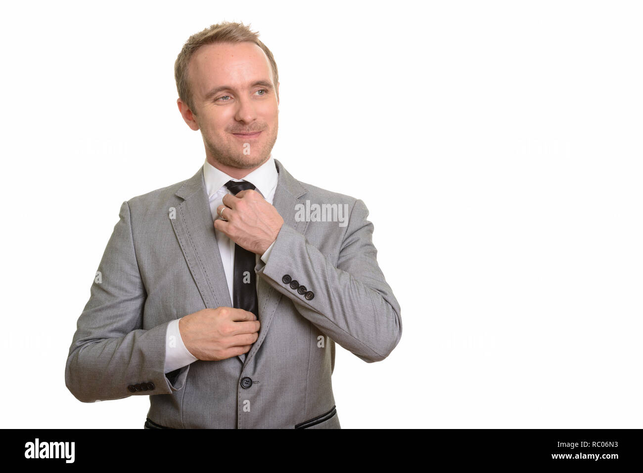 Stattlichen kaukasischen Geschäftsmann seine Krawatte vor weißem Hintergrund zur Festsetzung Stockfoto