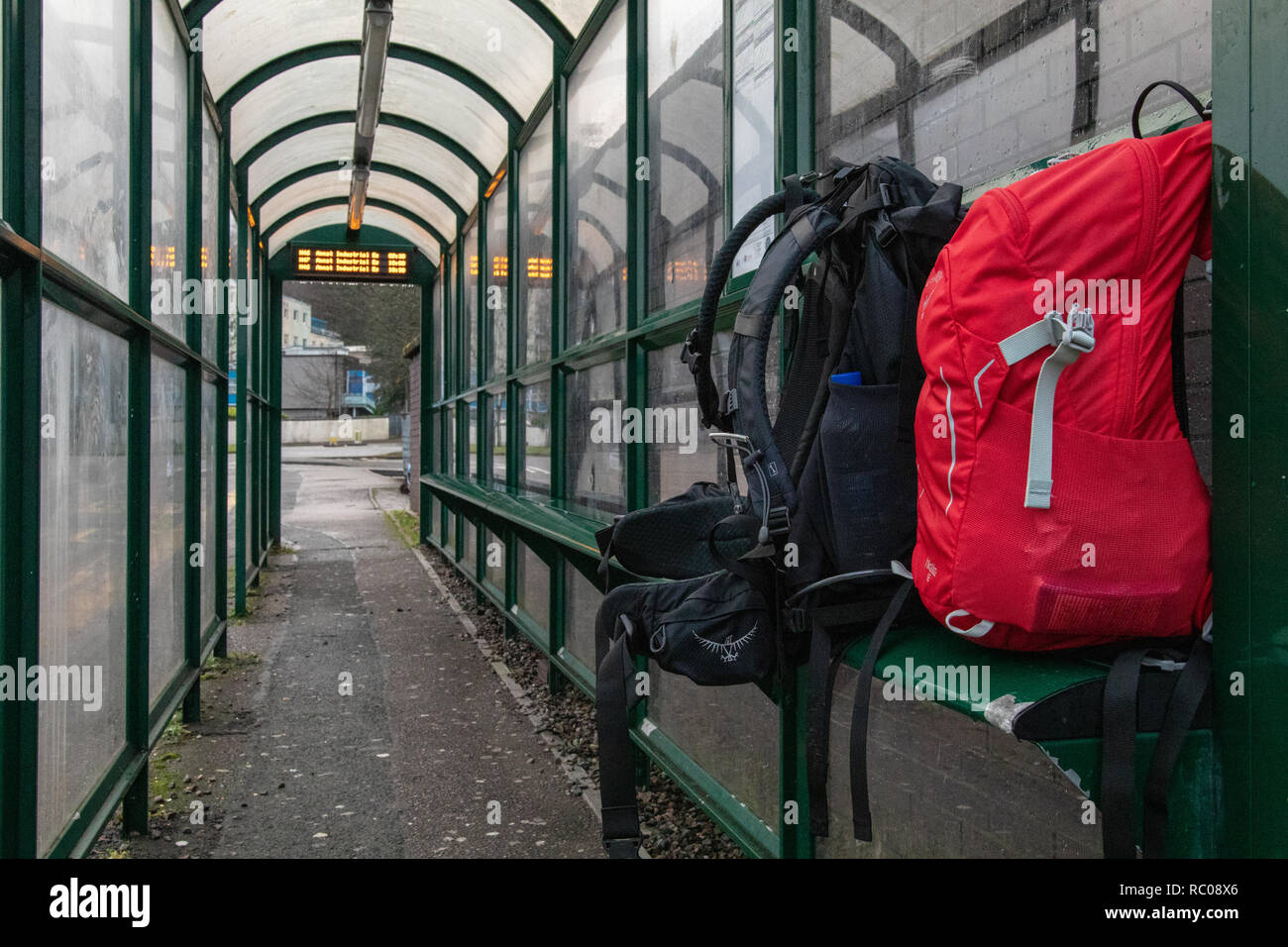 Zwei Reisetaschen Rot und Schwarz, Männer und Frauen warten auf den Bus in Schottland Highlands. Stockfoto