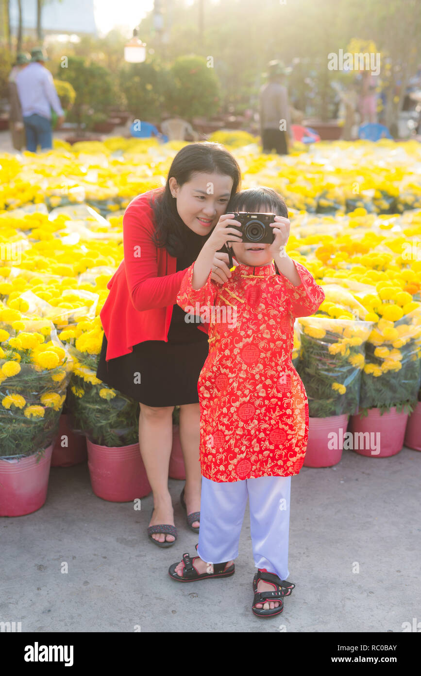 Little Boy und seine schöne junge Mutter mit der Digitalkamera. Happy Family, Foto in Tet Blumenmarkt. Im Freien. Stockfoto