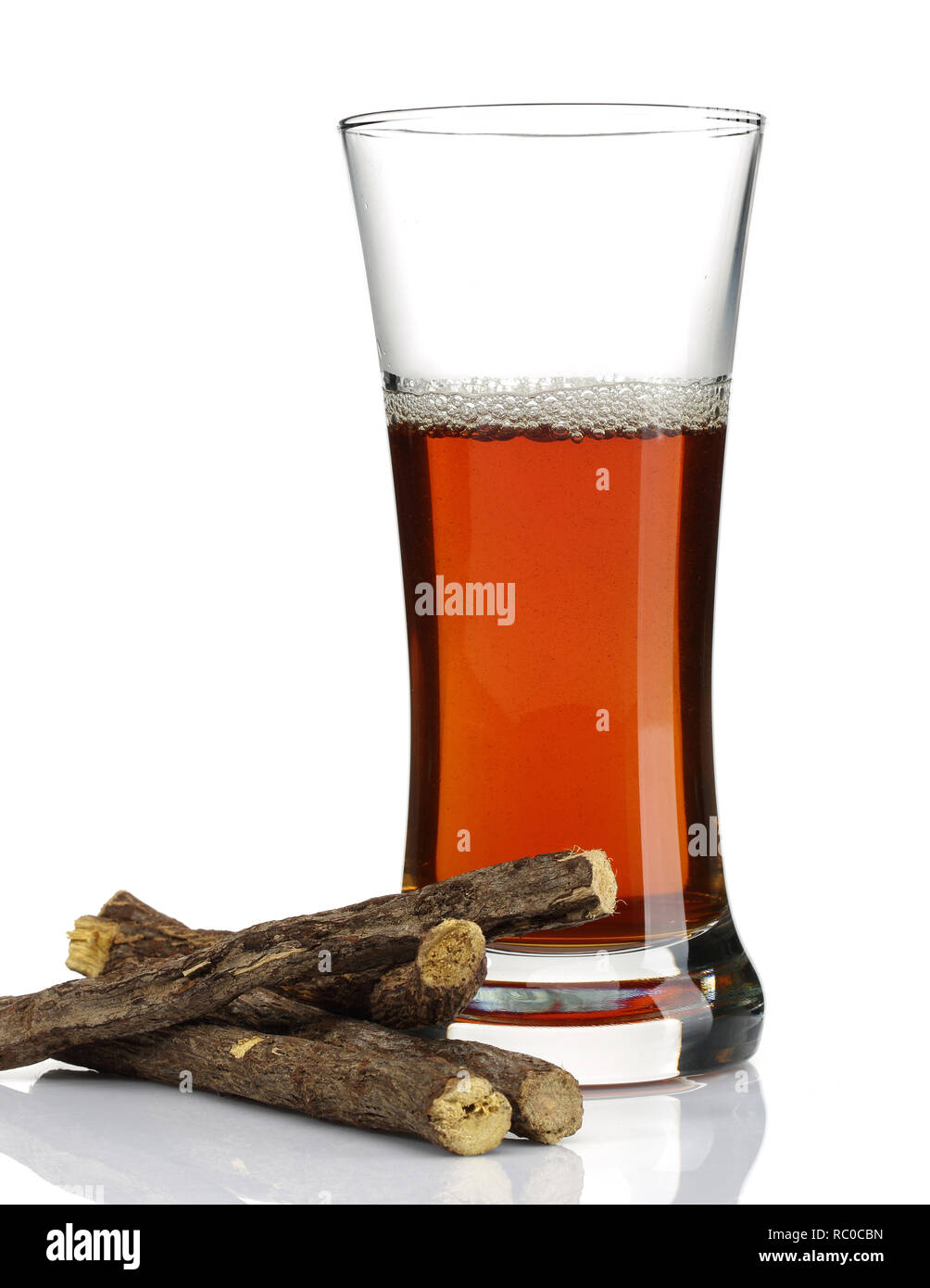 Süßholzwurzel und ein Glas Tee auf weißem Hintergrund Stockfoto