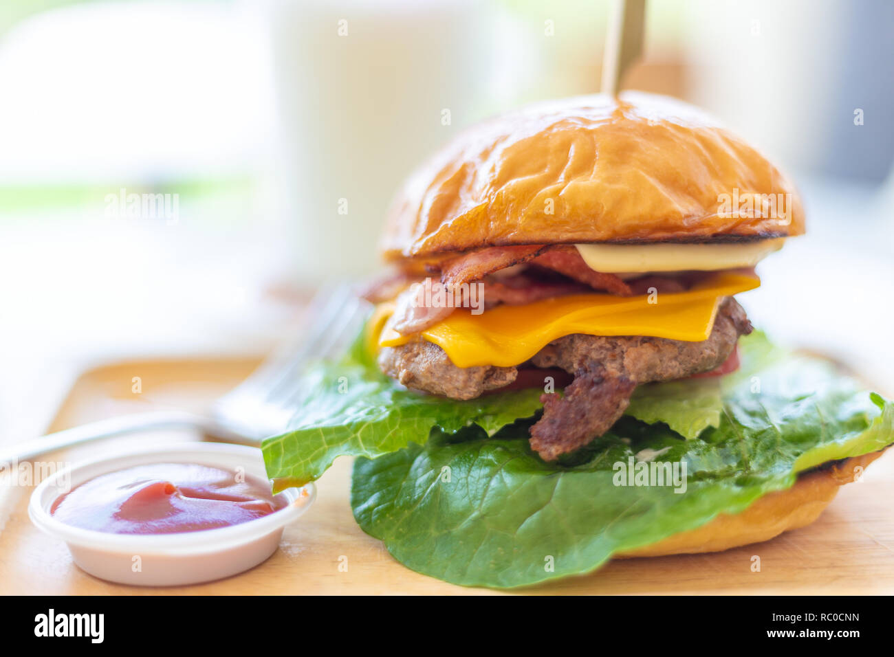 Hausgemachte stil Hamburger mit mehreren Schichten von Rindfleisch, Käse und Speck mit Ketchup Soße auf der Seite Stockfoto