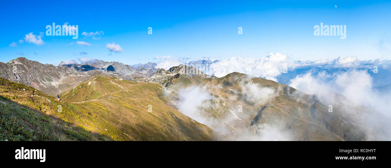 Panorama der Berggipfel Landschaft. Berglandschaft mit blauem Himmel und weißen Wolken. Panoramablick über den Wolken Stockfoto