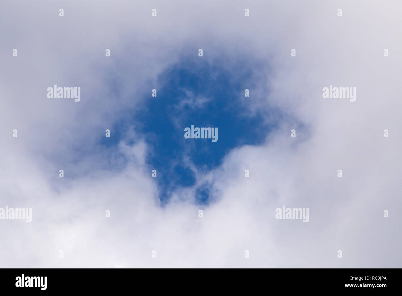 Blick auf den blauen Himmel durch das Loch in der Cloud Stockfoto