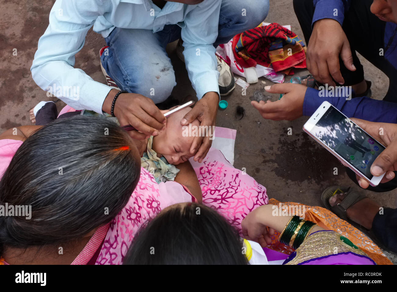 Ein Baby erhält seinen ersten Haarschnitt außerhalb Mumbadevi Tempel, Mumbai, Indien, das erste Haar geschnitten zu werden, ein wichtiges Hinduistisches Ritual Stockfoto