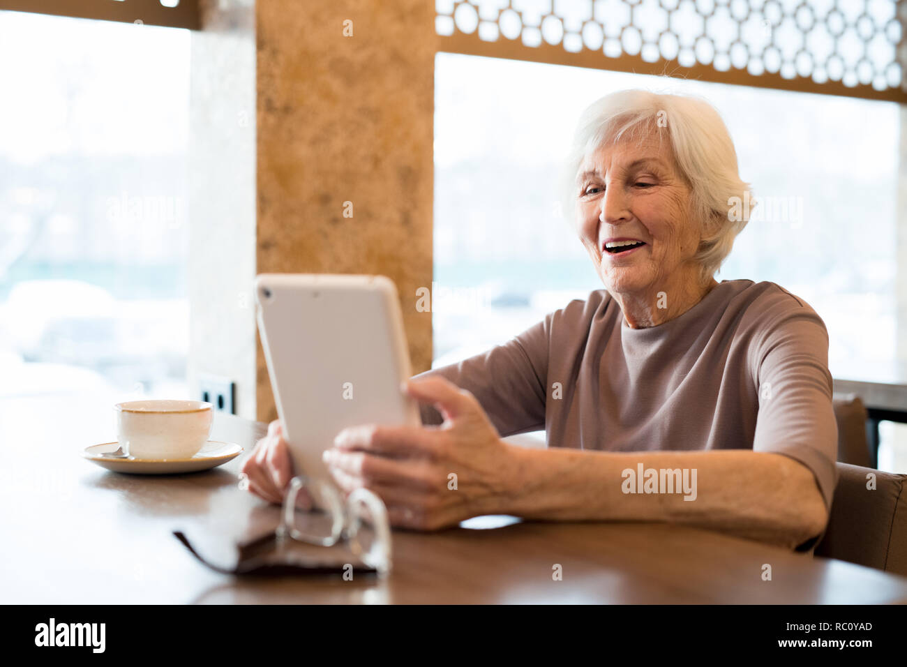 Fröhlich aufgeregt ältere Frau genießen Lesung im Cafe Stockfoto