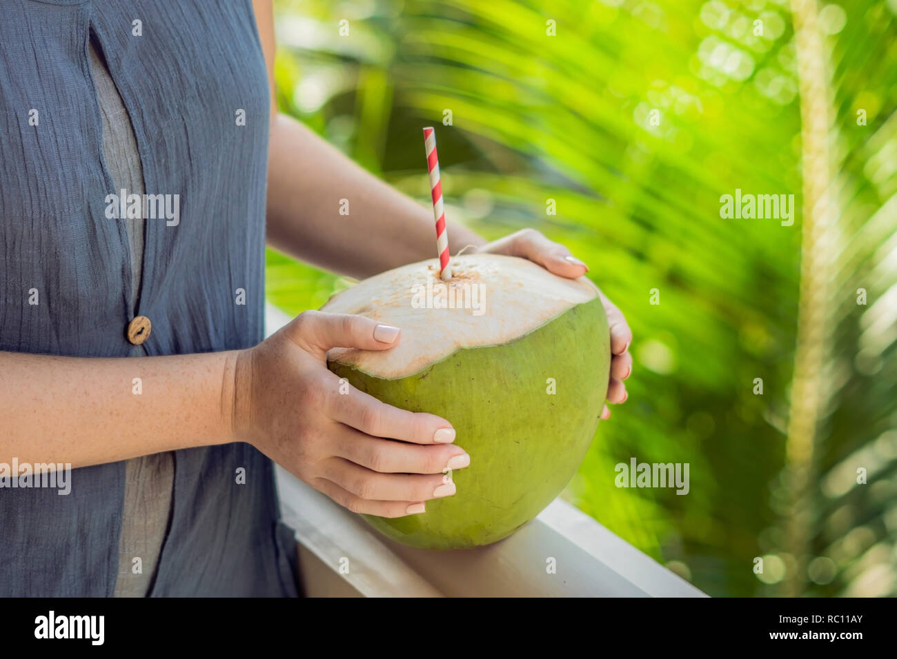 Kokosnuss in schöne weibliche Hände auf einem grünen Hintergrund. Die Vorteile der Kokosnuss Wasser Konzept. Stockfoto