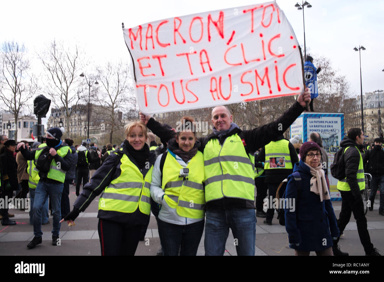 Paris, Frankreich. 12. Januar, 2019. Gilets Jaunes, Gelb, Demonstranten auf dem Place de la Bastille, zeigt ein Zeichen 'Macron und dein ganzes Volk, am Minimum salary" Credit: Roger Ankri/Alamy leben Nachrichten Stockfoto