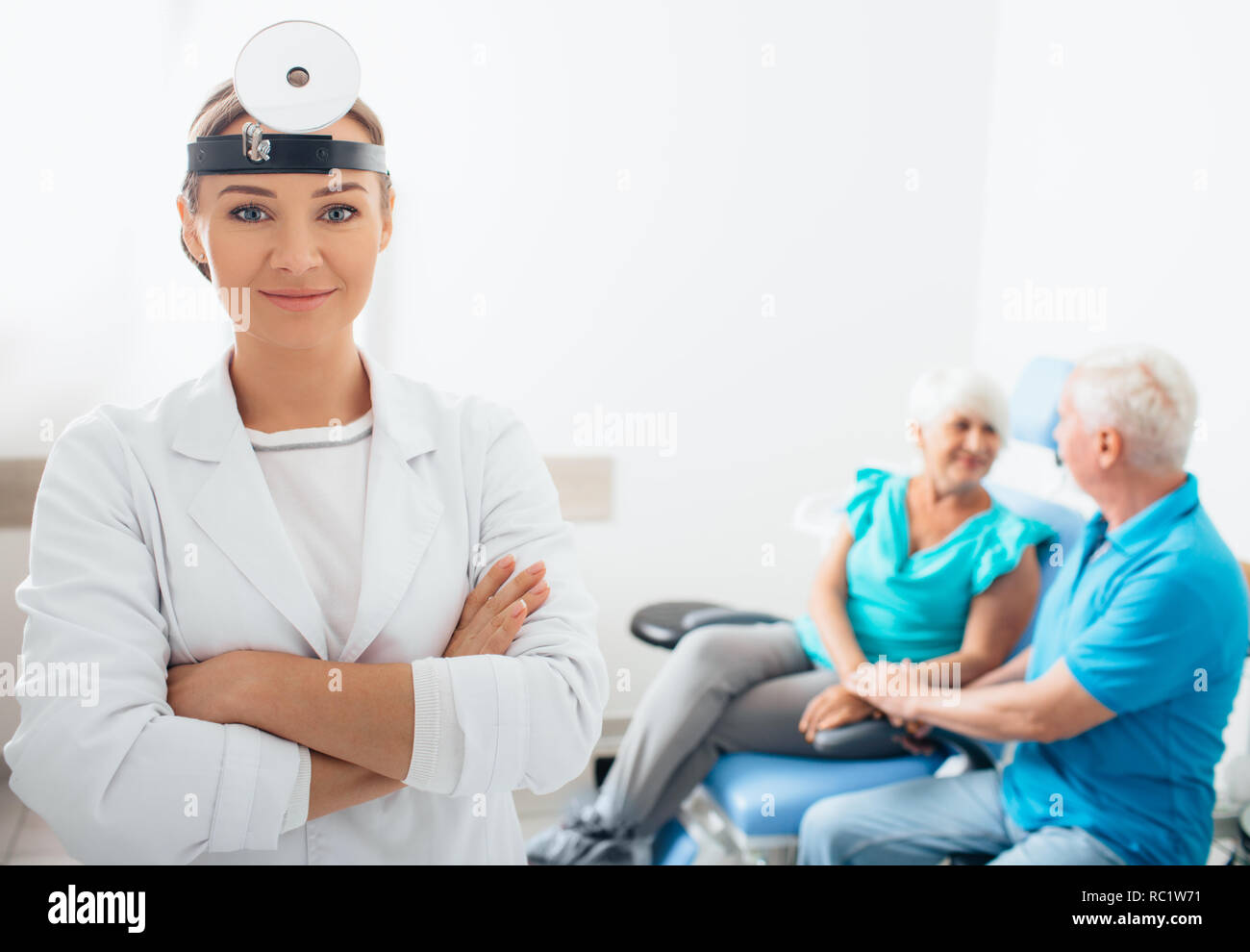 Lächelnd otolaryngologist Arzt mit ihr im Alter von Patienten im Hintergrund, im Vordergrund der medizinischen Zimmer konzentrieren Stockfoto