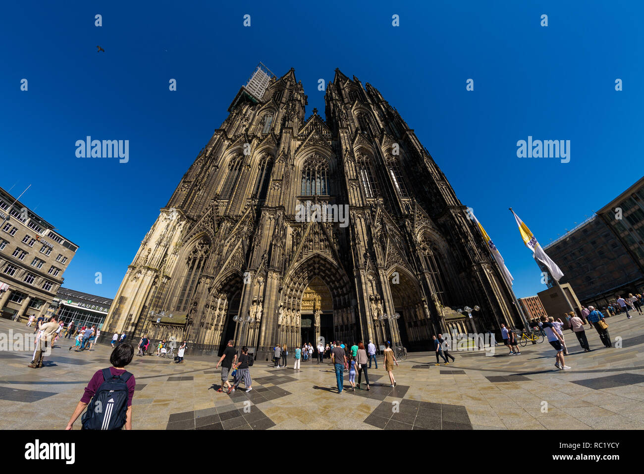 Weitwinkelaufnahme der äußeren Architektur der Kölner Dom, Deutschland, mit Einheimischen und Touristen in den angrenzenden Platz. Stockfoto