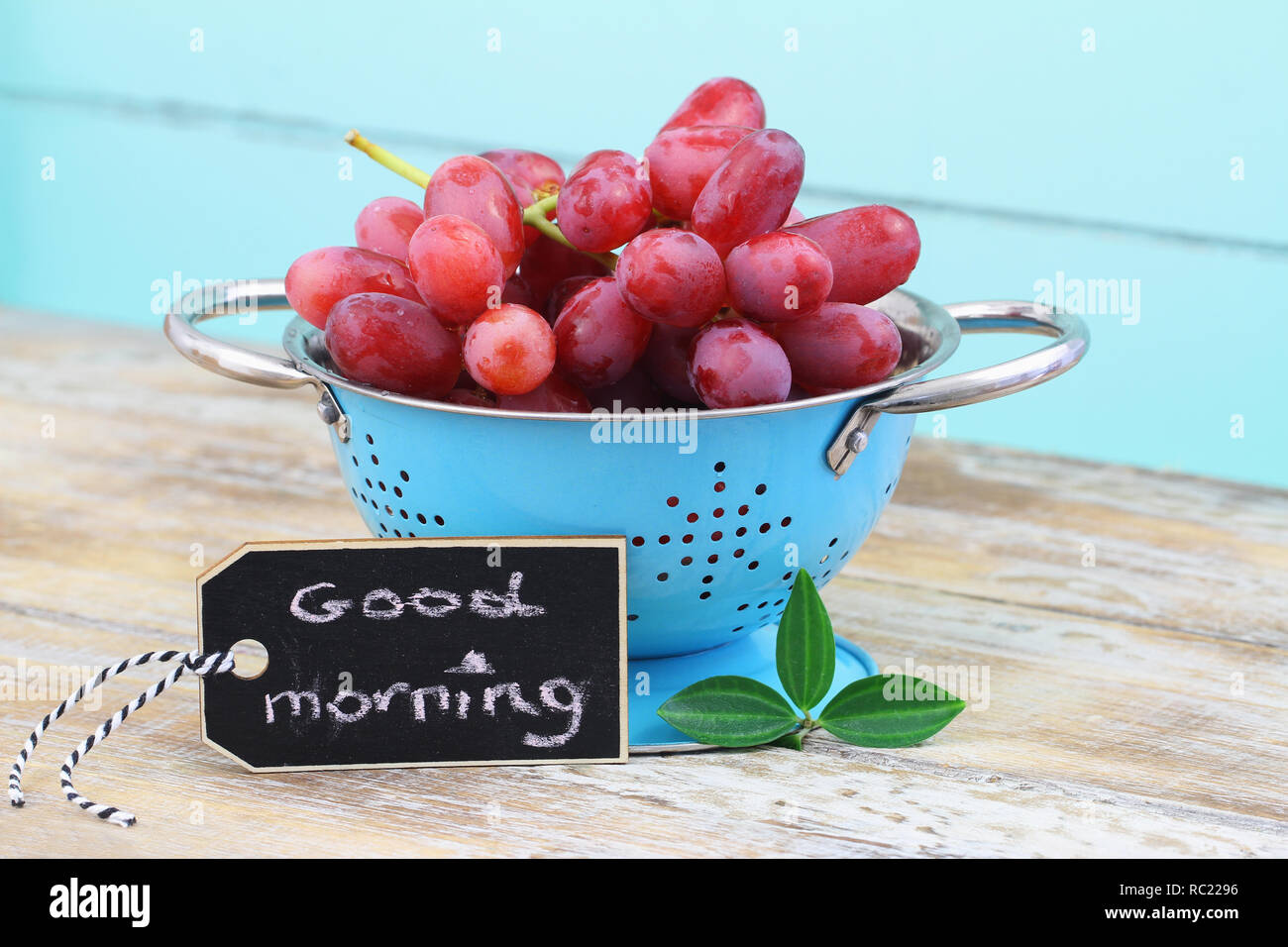 Guten Morgen Karte mit frischen roten Trauben blau Sieb auf Holz- Oberfläche Stockfoto