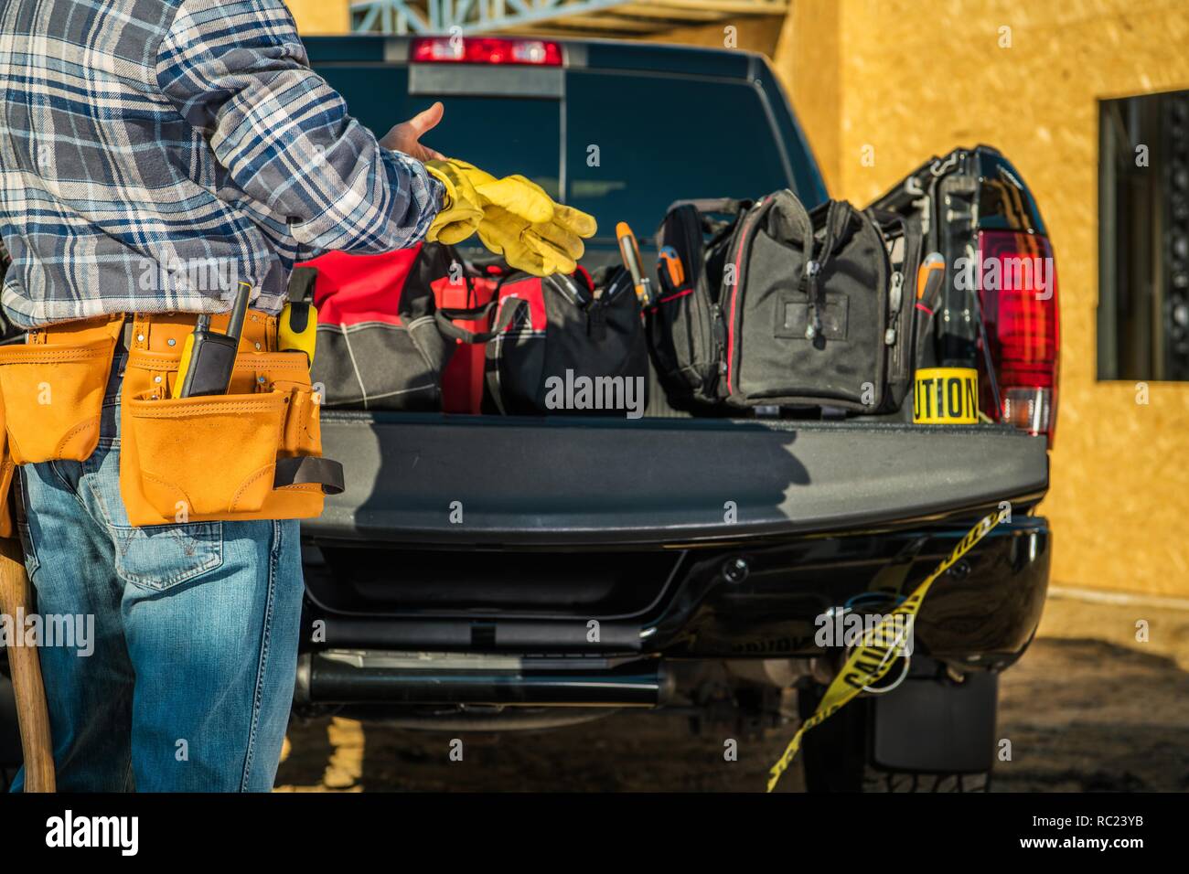 Bau Business Industrie. Kaukasische Auftragnehmer Arbeiter bereitet sich für den Job durch das Tragen von Schutzhandschuhen Vor seinem Pickup Truck voll o Stockfoto