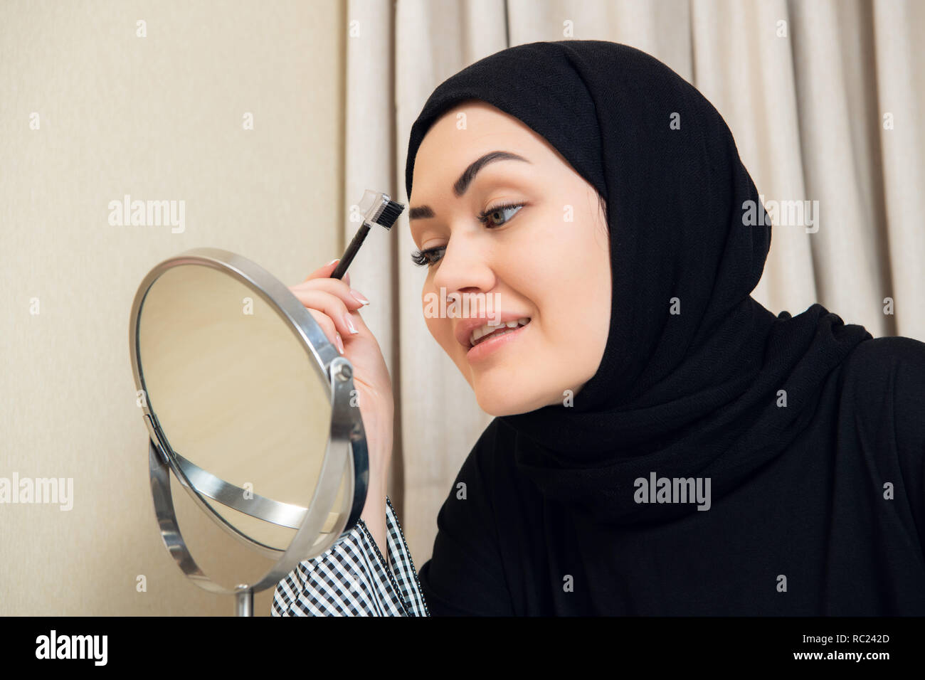 Eine junge muslimische Frau ihre Augenbrauen formen mit einer Bürste Stockfoto