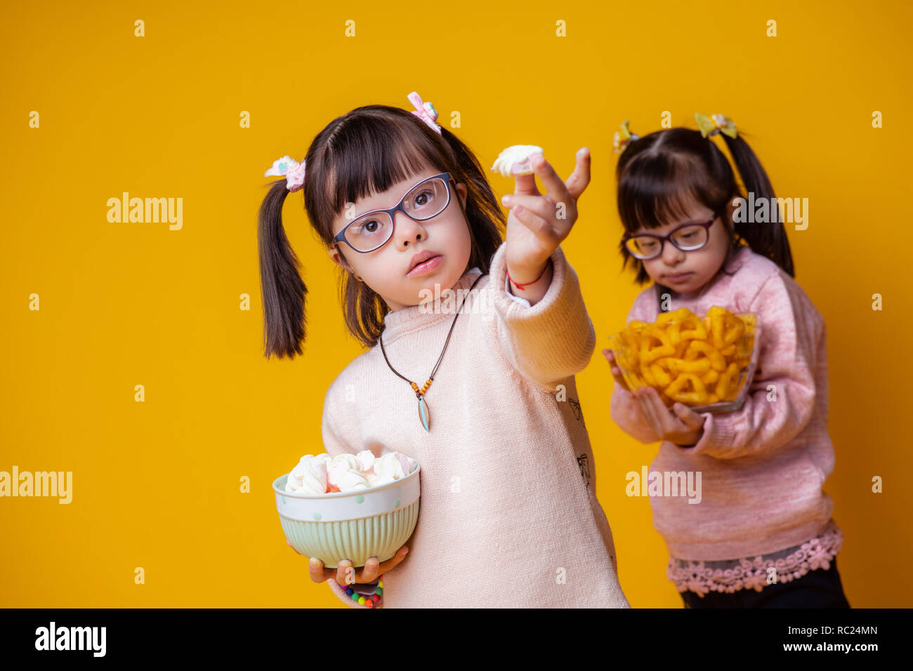 Ungewöhnlich ansprechend Kind ihr Essen, während Schwester hinter Stockfoto