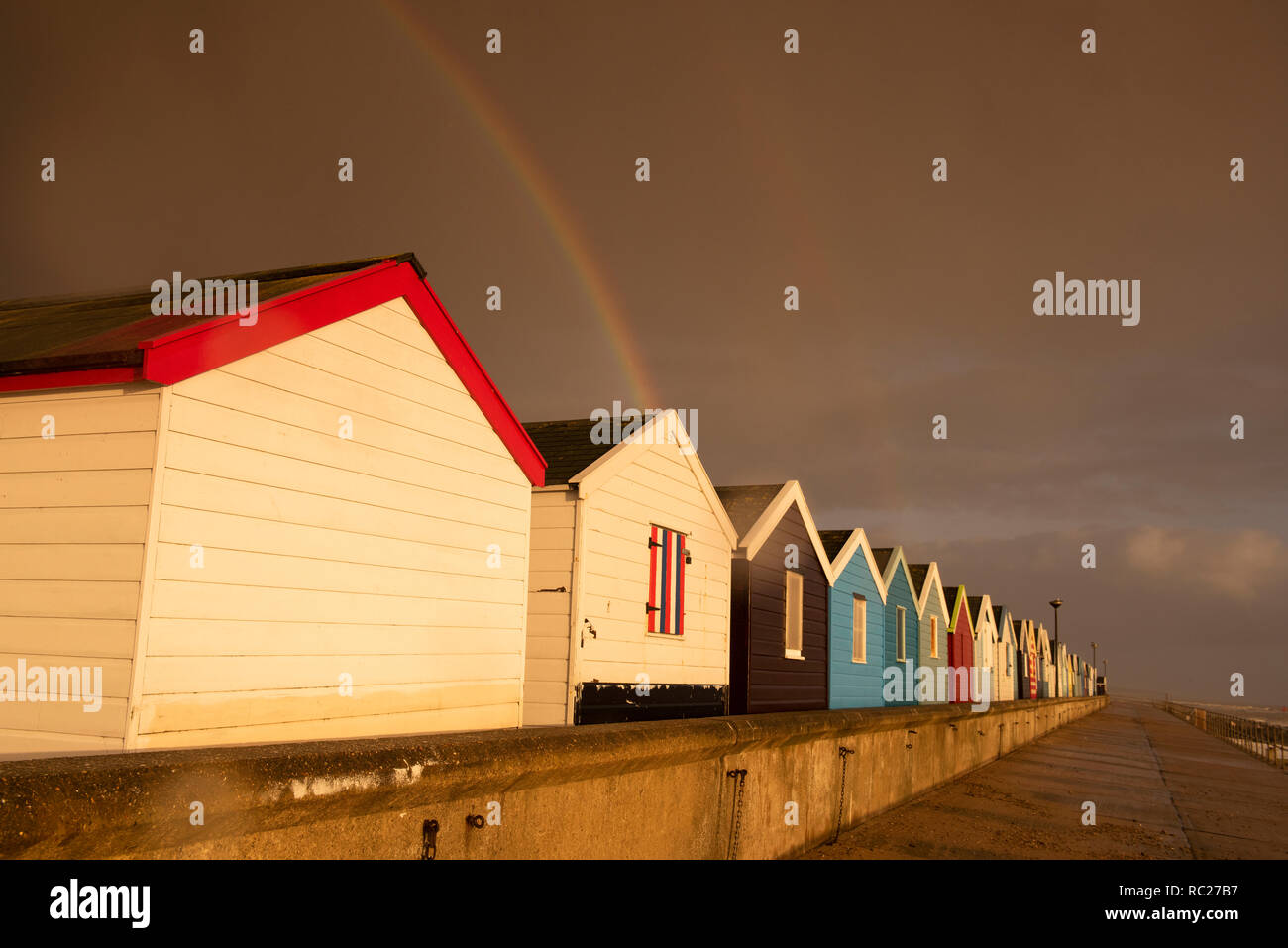 Regenbogen über Holzhütten am Southwold in Suffolk, England Großbritannien Stockfoto