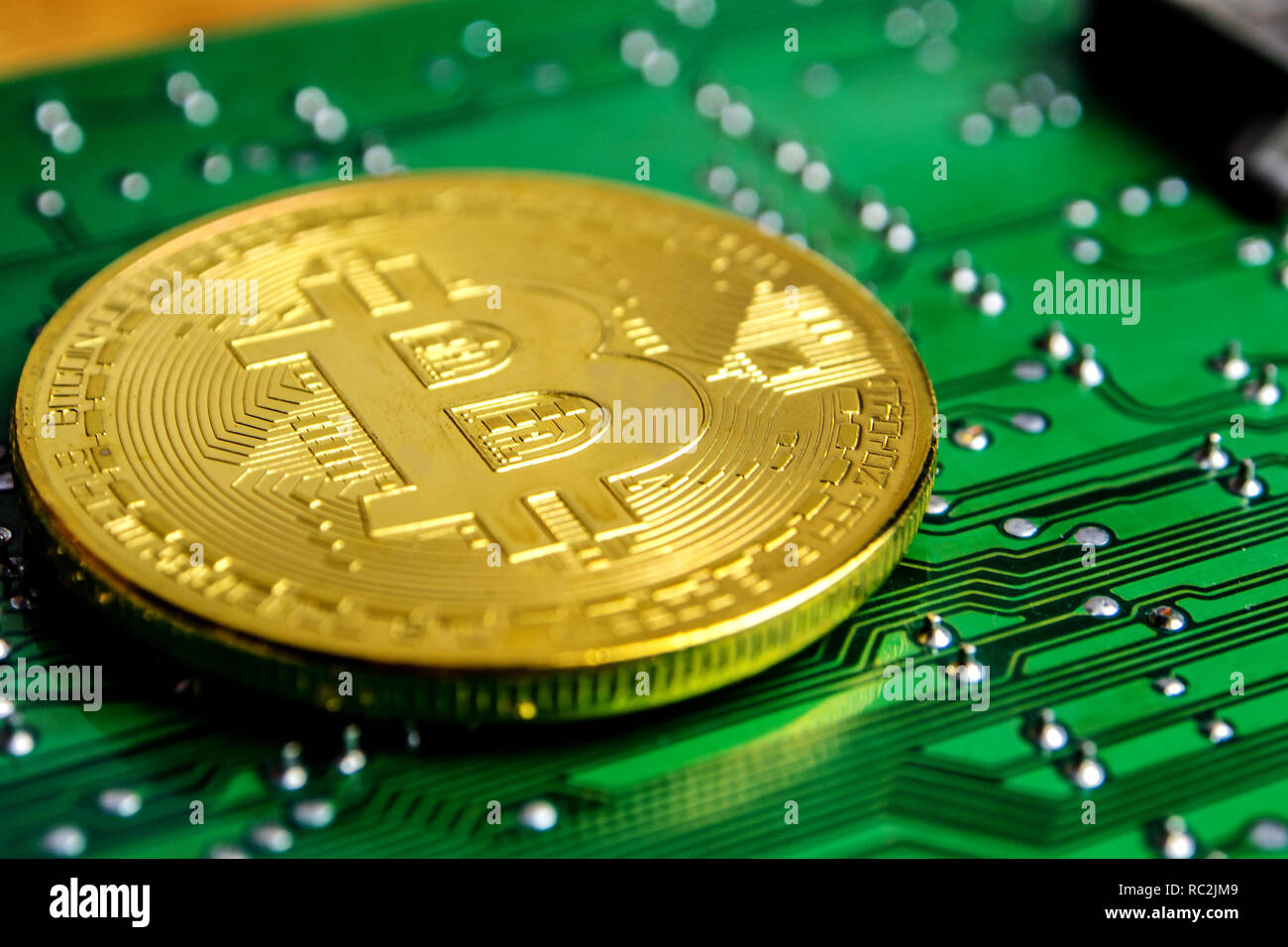 Nahaufnahme des Goldenen bitcoin Münze mit einem Data Processor, elektronische Computer Hardware Technologie und ihre Oberfläche mit grünem Hintergrund Stockfoto