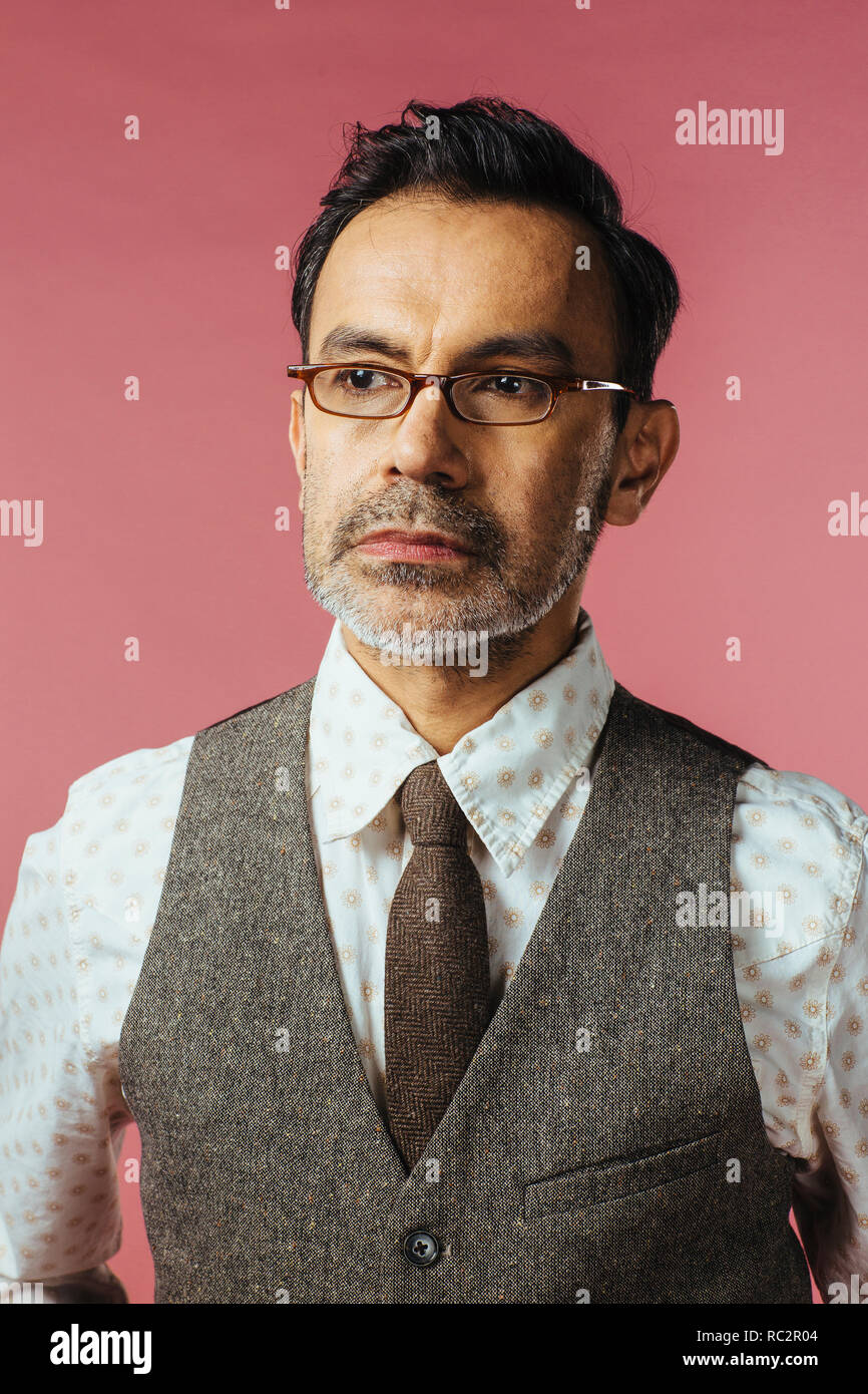 Porträt eines reifen Mannes in Weste und Gläser, isoliert auf Rosa Stockfoto