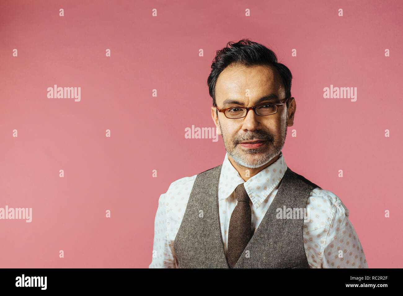Porträt einer reifer Mann im Hemd und Brille mit Kamera, isoliert auf Rosa Stockfoto