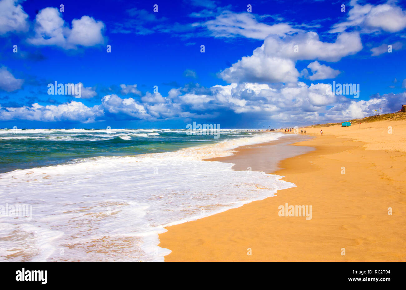 Schönen Sandstrand an der französischen Atlantikküste. Sonnigen Sommertag mit blauem Himmel und weißen Wolken und Wellen über einen breiten emp brechen Stockfoto