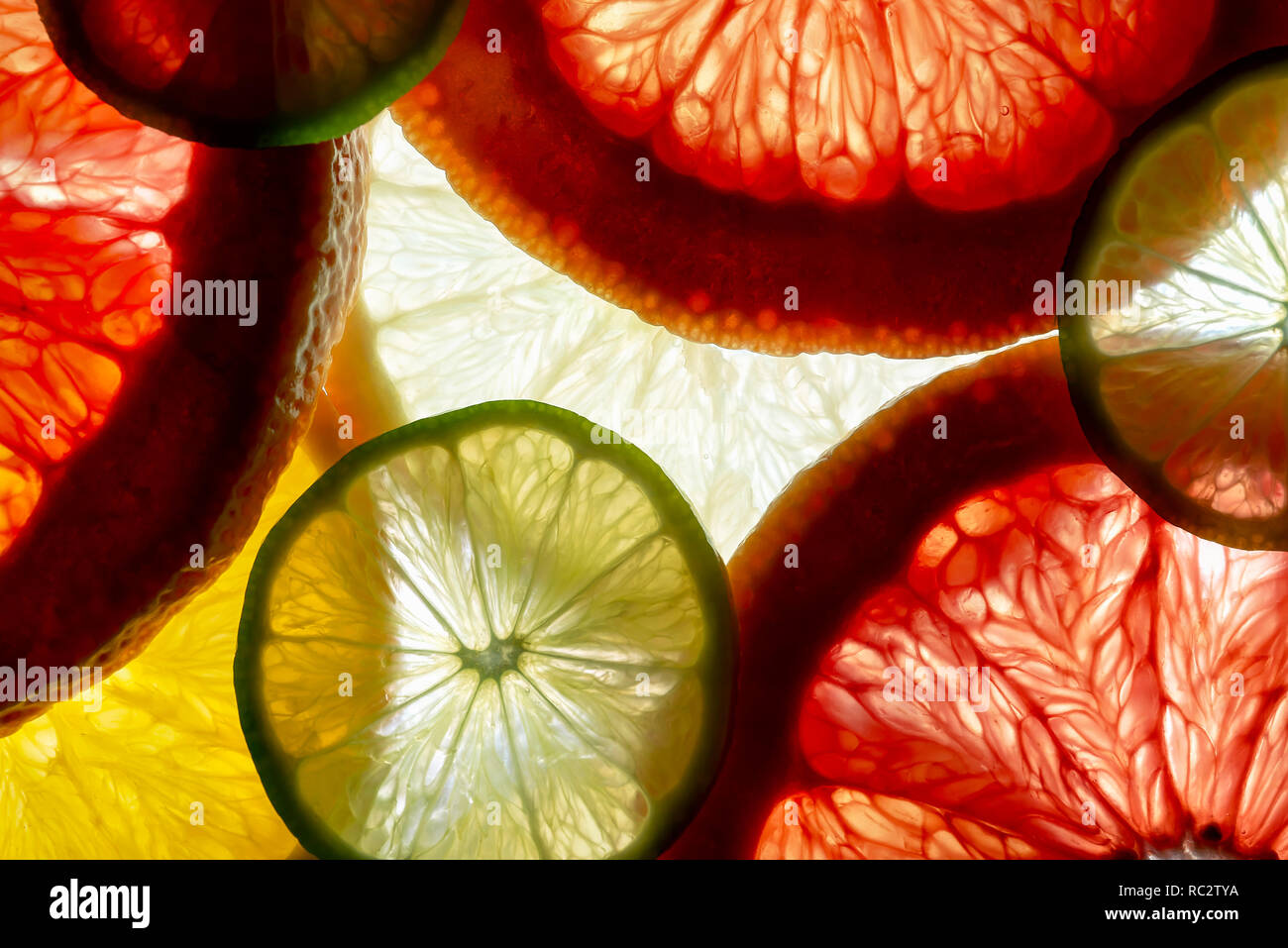 Bunt gemischt in Scheiben geschnittene Früchte orange, limone, Grapefruit, Zitrone. Hintergrund mit Hintergrundbeleuchtung Stockfoto