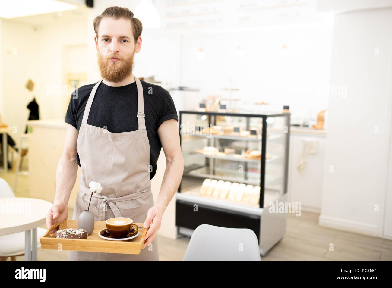 Hübscher junger barista Durchführung fach mit Cappuccino Stockfoto