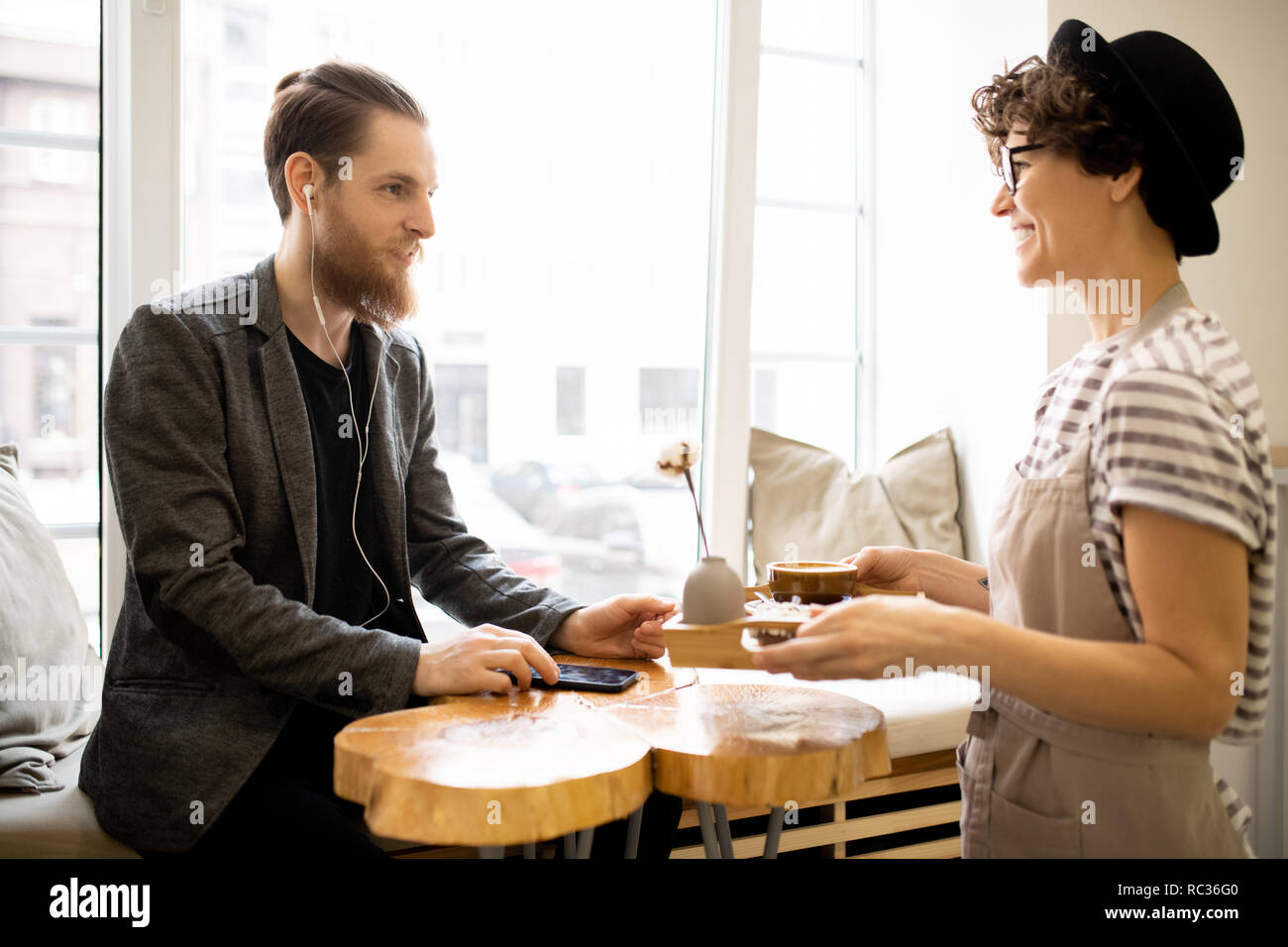 Positive Kellnerin, Tablett mit Kaffee an Kunden Stockfoto