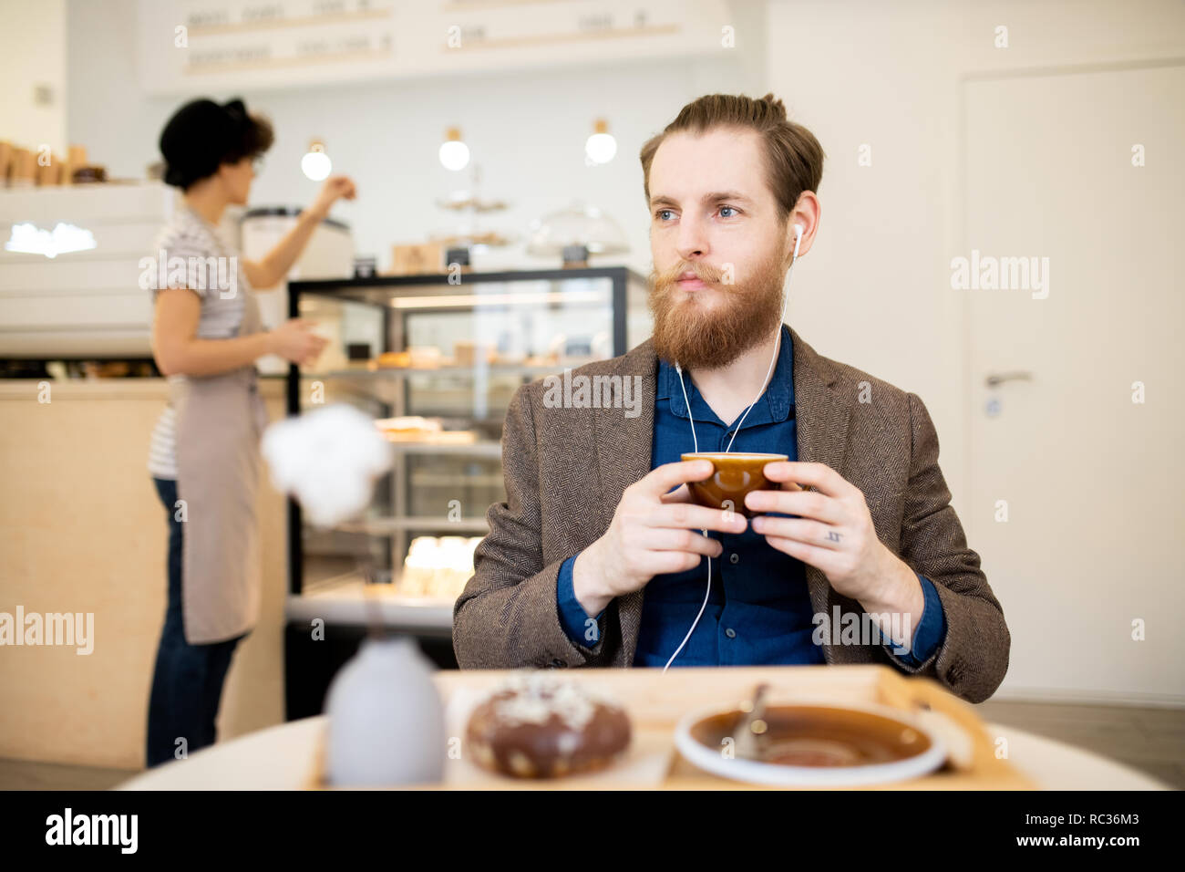 Nachdenklicher Mann in Ohrhörer entspannen im Coffee Shop Stockfoto