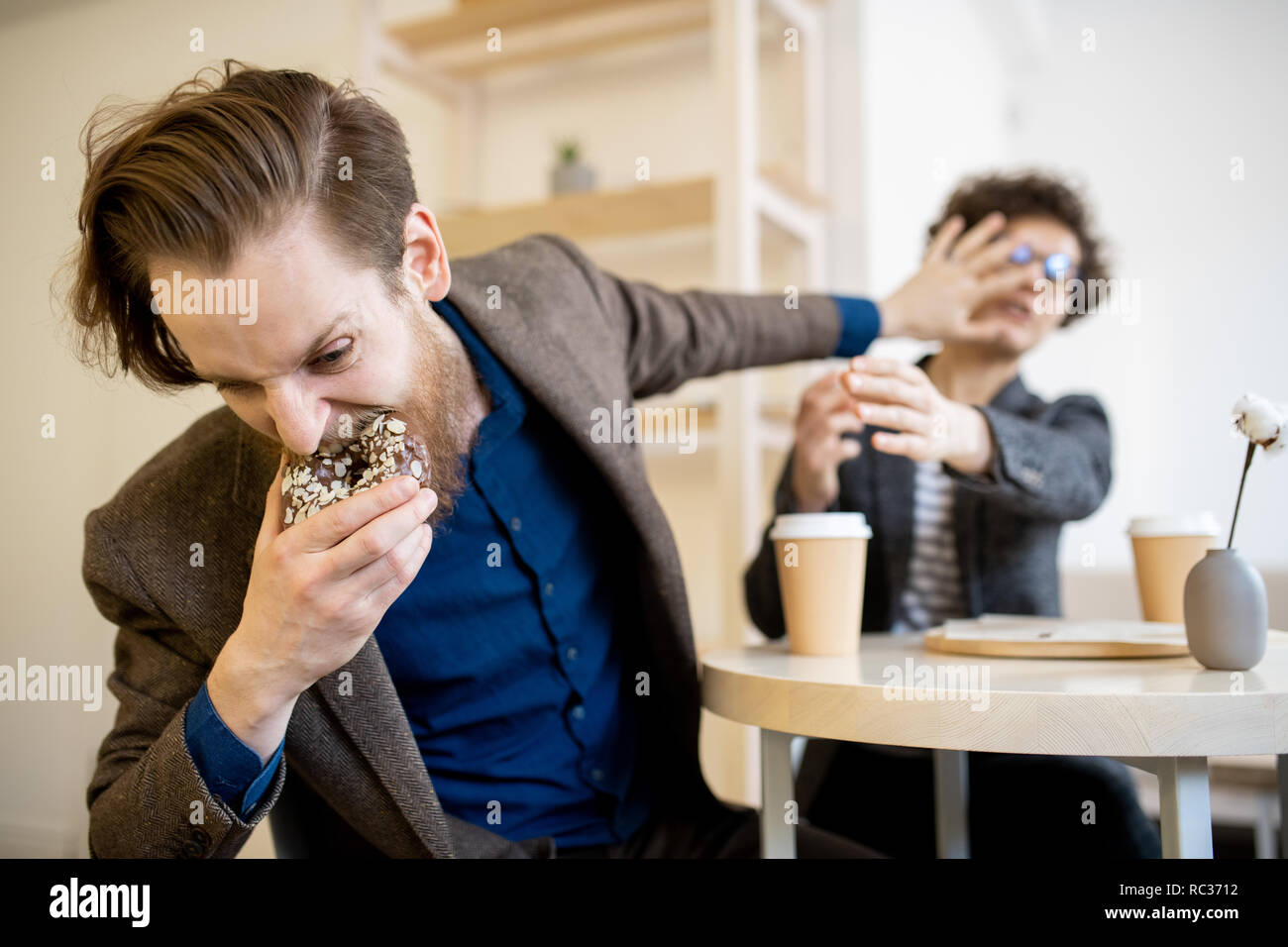 Hungrigen mann Donut aus Frau Stockfoto