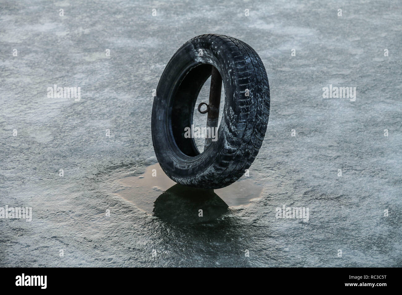 Alte schwarze Reifen in Seewasser im Winter Zeit eingefroren. Stockfoto