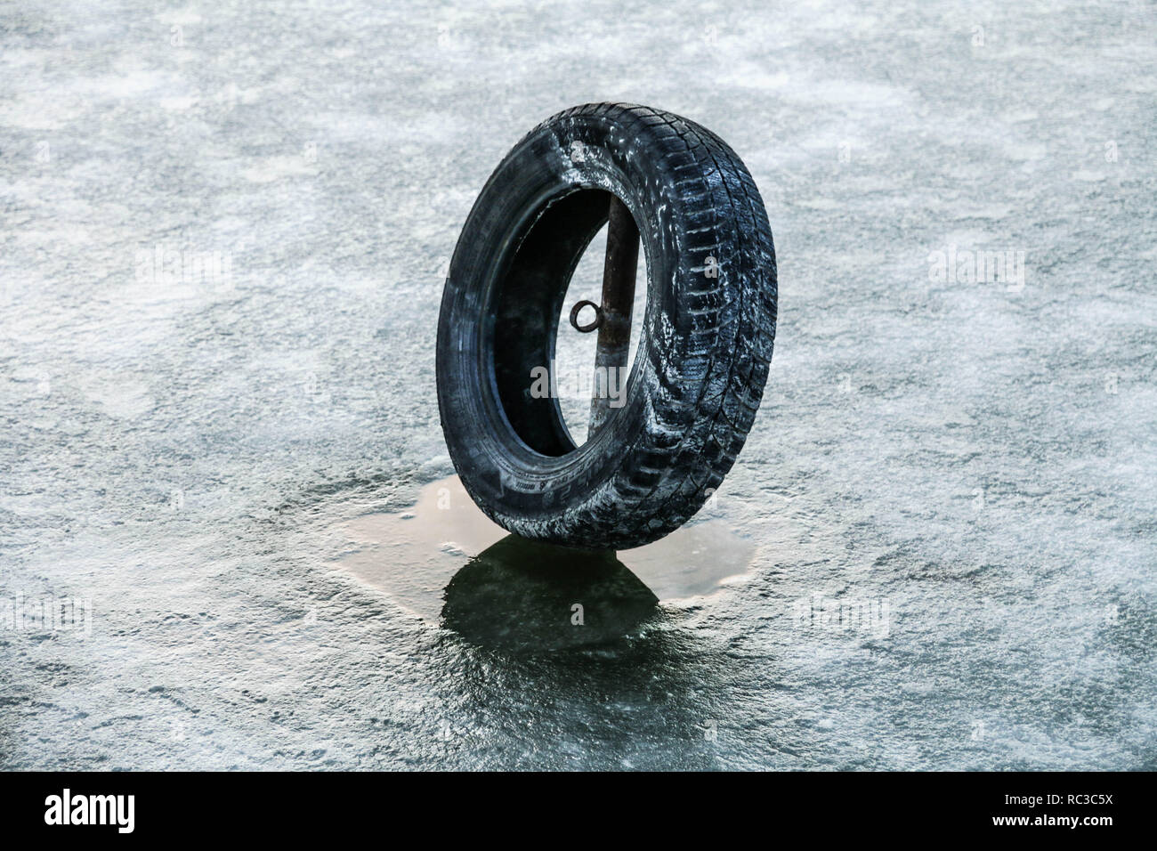 Alte schwarze Reifen in Seewasser im Winter Zeit eingefroren. Stockfoto