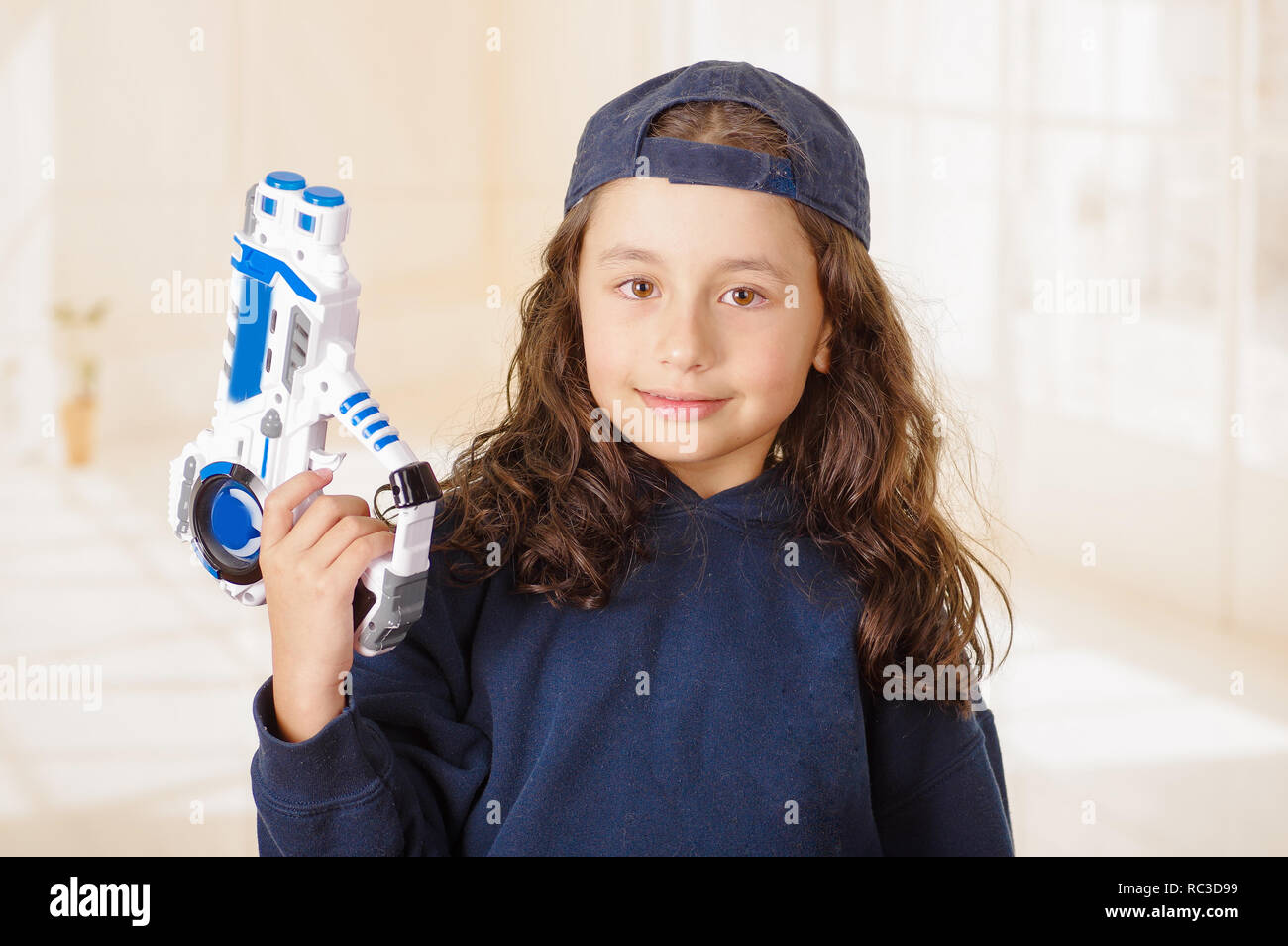 Glückliche kleine Mädchen, dass eine Waffe in der Hand und tragen junge Kleidung Stockfoto