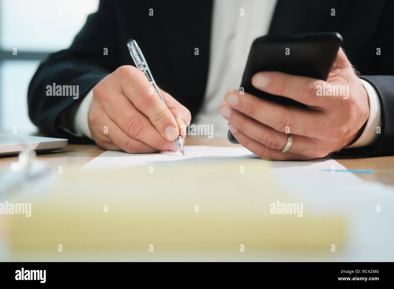 Hände von Business Mann das Schreiben mit Stift und Holding Tel. Stockfoto