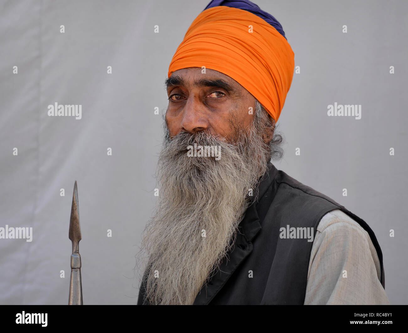 Ältere Menschen, bewaffneten Krieger (Indische Sikhs nihang) mit orangefarbenen Turban und traditionellen Lanze/Speer posiert für die Kamera. Stockfoto