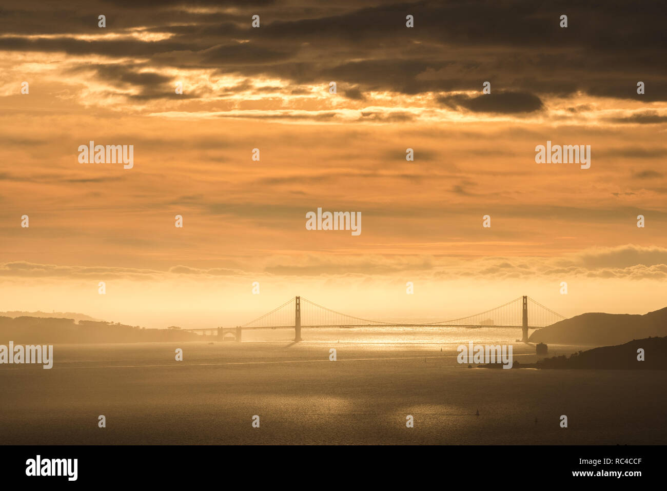 Die Golden Gate Bridge in San Francisco von weit weg in die Berkeley Hills bei einem wunderschönen Sonnenuntergang zu sehen, wenn der Himmel war orange. Stockfoto