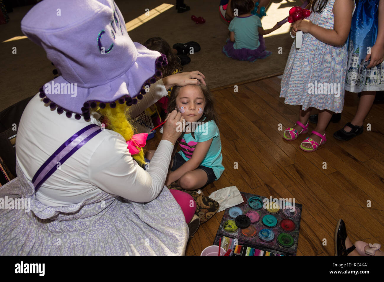 Clown Künstler Malerei Make-up für ein kleines Mädchen auf einer Party event. Stockfoto