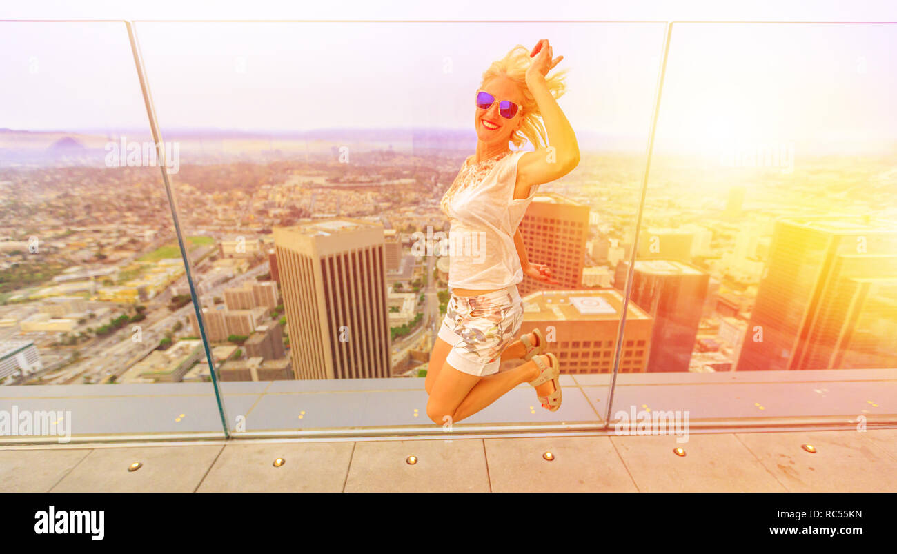 Blonde Frau mit Blick von oben auf die Stadt Los Angeles in Kalifornien, USA. Touristische Überbrückungskabel an die Innenstadt von LA Skyline bei Sonnenuntergang. Reise und Tourismus amerikanische Konzept. Stockfoto