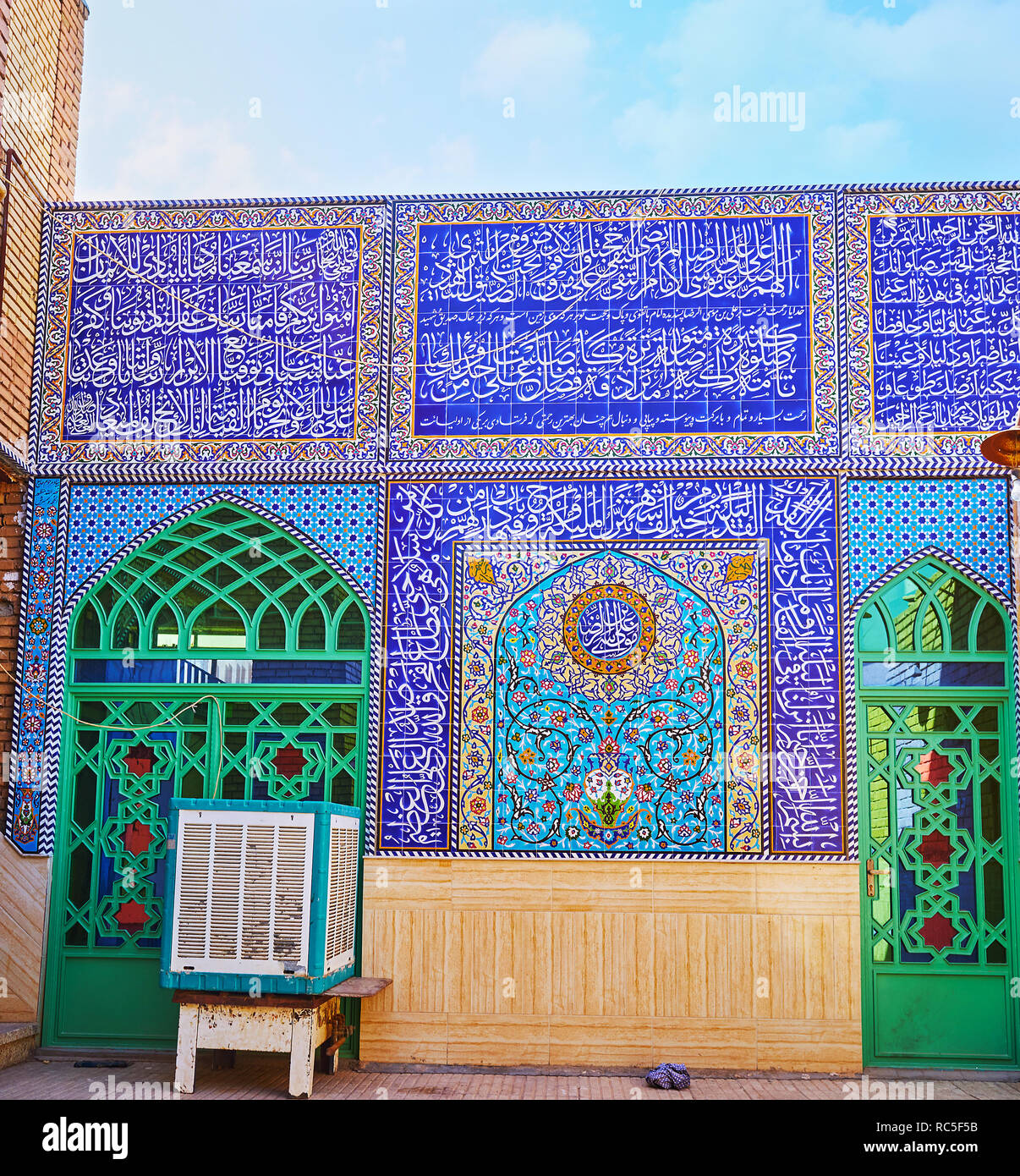 Die Fassade an der Wand des alten Mausoleum in der historischen Altstadt von Yazd mit kunstvollen Fliesen- muster und koranischen Kalligraphie um die Glasfenster Türen, Iran. Stockfoto