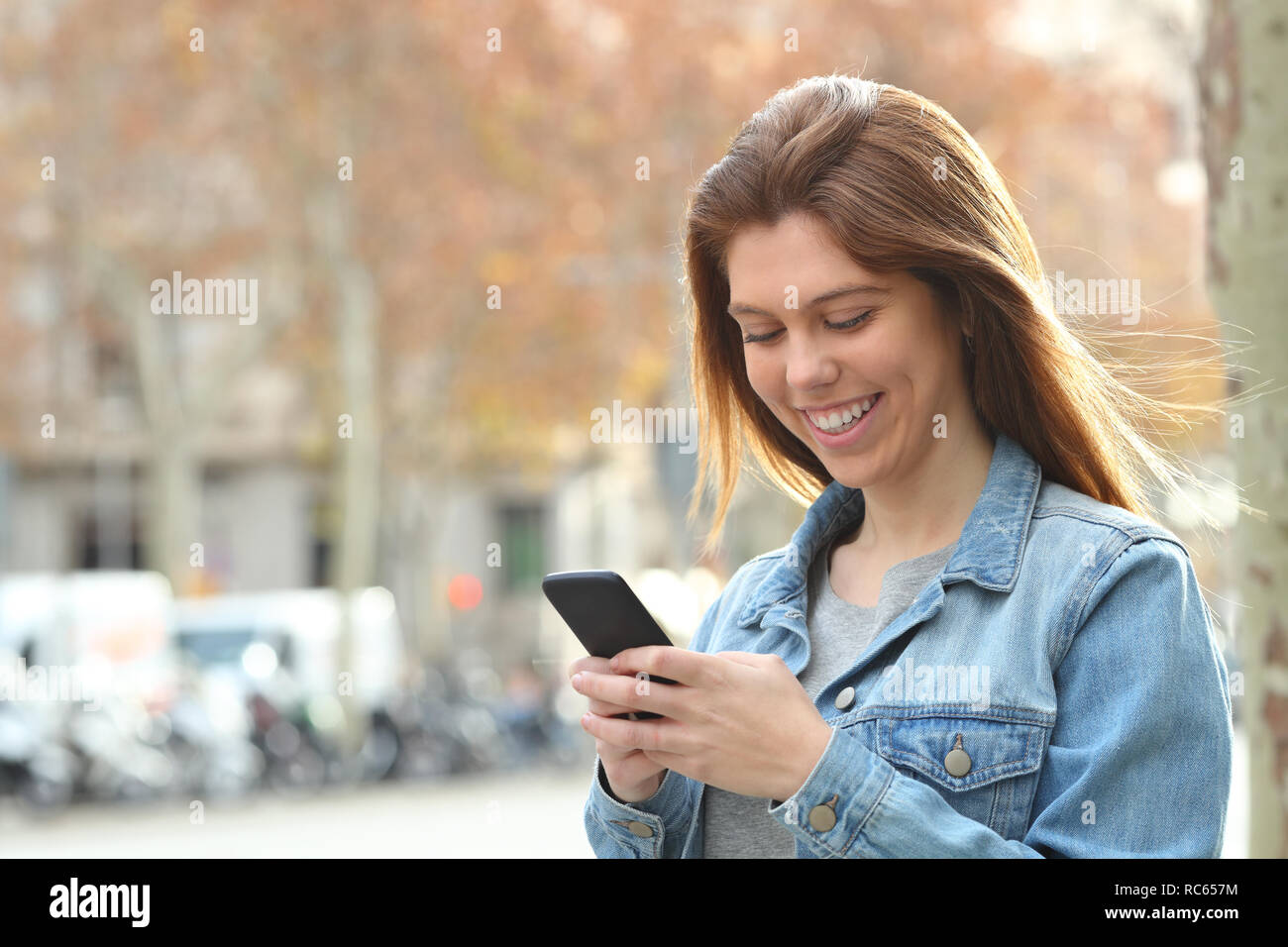 Happy Jugendmädchen Textnachrichten auf Smart Phone zu Fuß auf der Straße Stockfoto